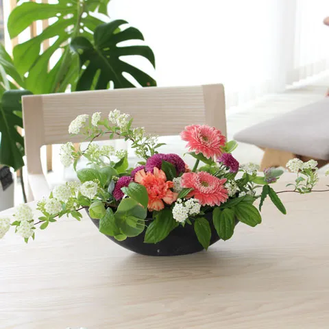 葉と色とりどりの花々を活けたテーブルフラワー