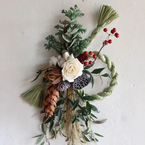 白いバラと松ぼっくり、赤い実を組み合わせた、冬の正月飾り