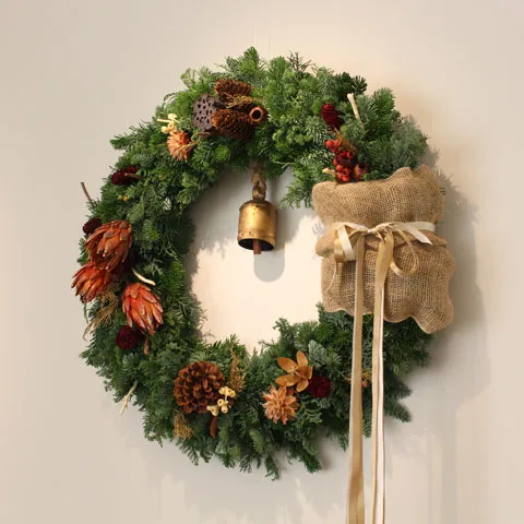 モミの枝と松ぼっくりで作られた、鈴付きのクリスマスリース