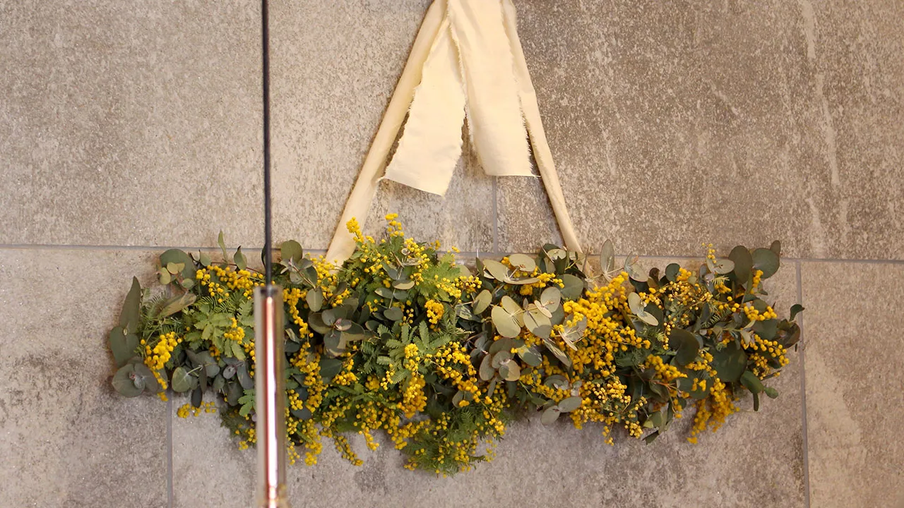 ミモザの黄色い花と緑の葉で作られた、壁掛けのドライフラワーアレンジ