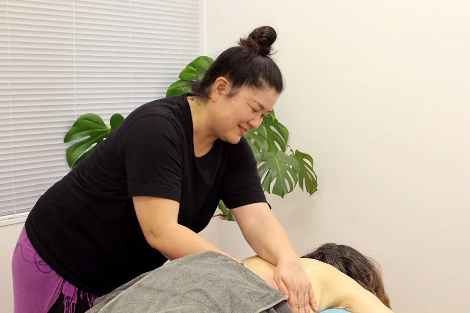 古代ハワイ伝統ロミロミオイルマッサージで背中をほぐす女性セラピストの施術風景