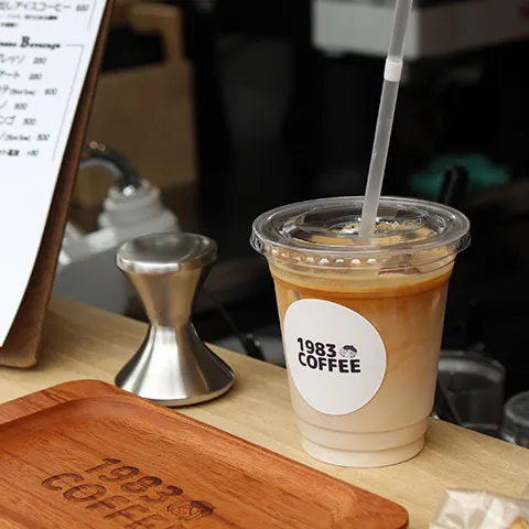 1983コーヒーのメニュー表と自家焙煎スペシャルティコーヒーが並ぶカウンター
