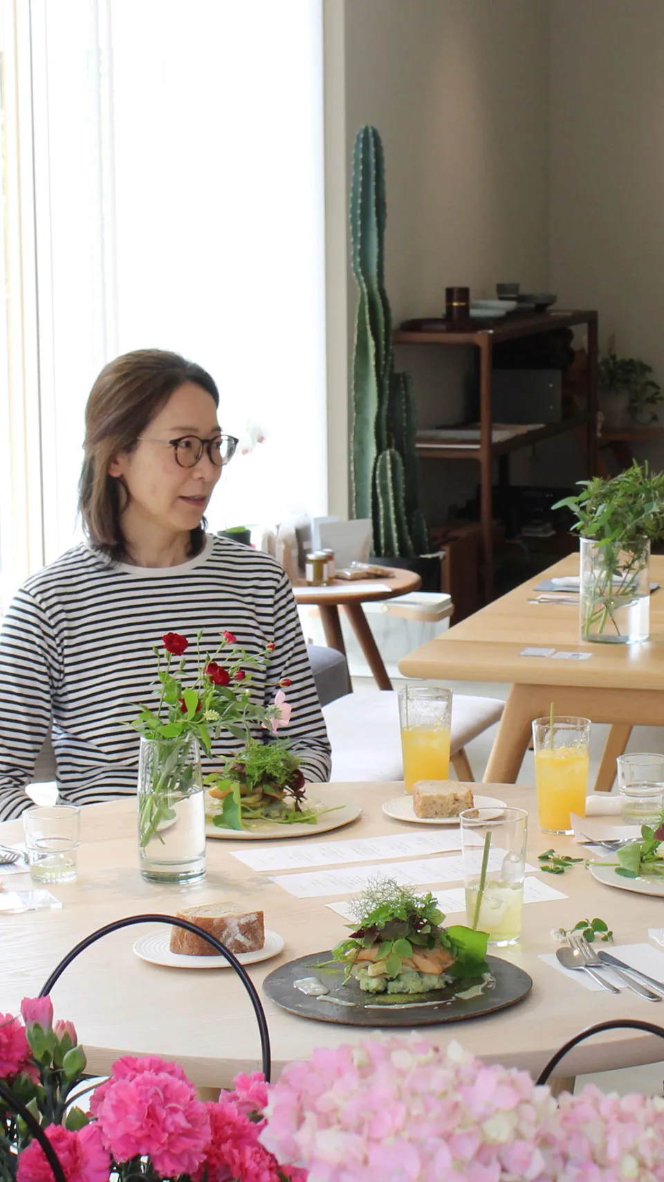 モダンな雰囲気の花ノキッチンで、テーブルに赤い花と共に食事を楽しむ女性たち。