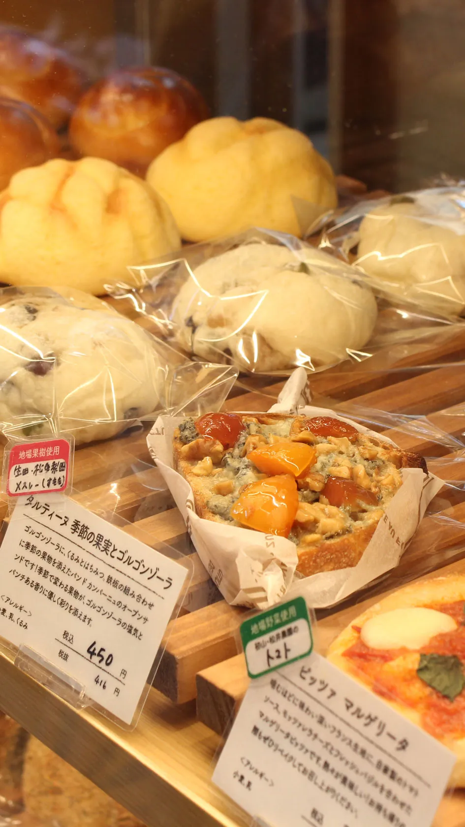 めぐみ焼菓子店の棚に並ぶ、色とりどりの焼きたてのパンとペストリー。